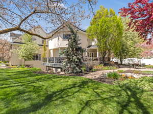 Back of property with stucco siding, a lawn, and solar panels