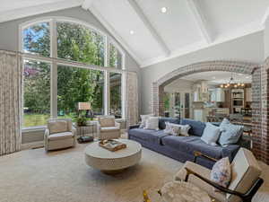 Living room featuring a notable chandelier, high vaulted ceiling, beamed ceiling, and arched walkways