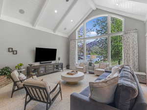 Living room with beam ceiling, high vaulted ceiling, light colored carpet, and recessed lighting
