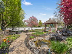 View of community with fence, a garden pond, a gazebo, and a patio