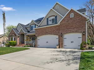 Craftsman-style house with a garage, brick siding, a front yard, and concrete driveway