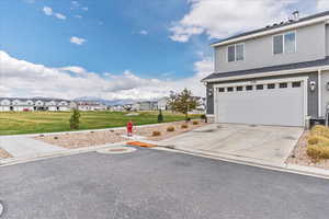 Traditional home with an attached garage, driveway, a front lawn, and a residential view
