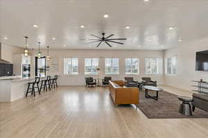 Living area with ceiling fan, recessed lighting, baseboards, and light wood-type flooring