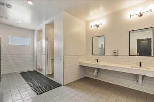 Bathroom featuring curtained shower, tile patterned flooring, visible vents, tile walls, and a textured ceiling