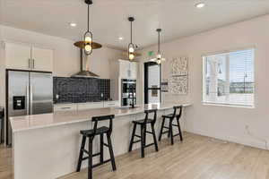Kitchen featuring a sink, decorative backsplash, light wood-type flooring, stainless steel appliances, and a peninsula