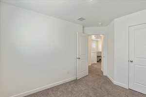 Unfurnished bedroom with baseboards, visible vents, and light colored carpet