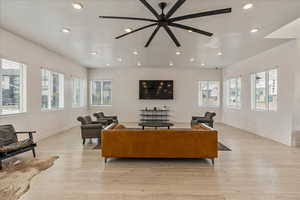 Living area with light wood-type flooring, a ceiling fan, baseboards, and recessed lighting