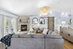 Living room with a fireplace, lofted ceiling, visible vents, and wood finished floors