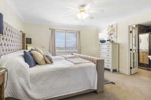 Bedroom featuring baseboards, light colored carpet, a ceiling fan, ensuite bath, and ornamental molding