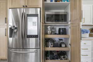 Kitchen featuring light brown cabinets, light countertops, and appliances with stainless steel finishes