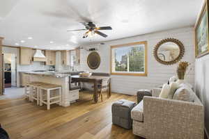 Living area featuring recessed lighting, a ceiling fan, wooden walls, and light wood-style flooring