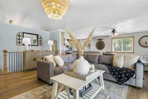 Living room with lofted ceiling, a ceiling fan, crown molding, and light wood-type flooring