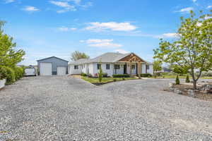 View of front of house featuring driveway, an outbuilding, covered porch, and a garage