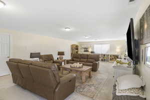 Living area with arched walkways, visible vents, and light carpet