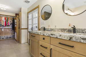 Bathroom with a walk in closet, a sink, visible vents, and double vanity