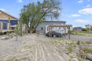 Rear view of property featuring a carport, a pergola, and a wooden deck