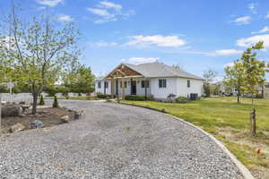 View of front of property with a front lawn, a porch, a shingled roof, and curved driveway