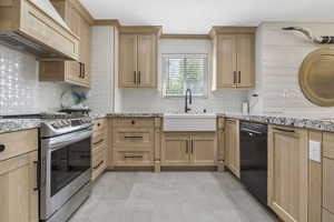 Kitchen with dishwasher, light brown cabinets, a sink, premium range hood, and stainless steel stove