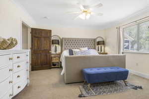 Bedroom with crown molding, light colored carpet, and a ceiling fan