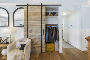 Sitting room featuring wood finished floors, a wainscoted wall, and visible vents