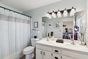 Bathroom featuring double vanity, a sink, curtained shower, and toilet