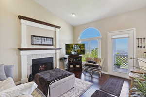 Living room featuring dark wood-style floors, vaulted ceiling, and a tile fireplace