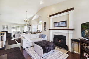 Living area featuring high vaulted ceiling, a chandelier, a healthy amount of sunlight, and a fireplace