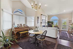 Dining space featuring a notable chandelier, a fireplace, high vaulted ceiling, recessed lighting, and wood finished floors