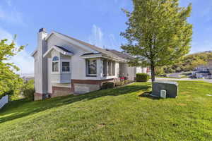 View of property exterior with a yard, a chimney, and stucco siding