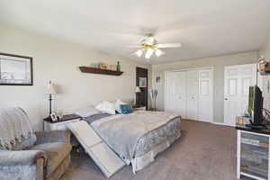 Carpeted bedroom with a ceiling fan and a closet