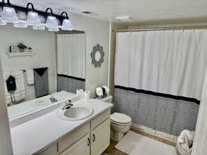 Full bath featuring curtained shower, toilet, and vanity