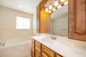 Bathroom with a textured ceiling, a garden tub, toilet, and vanity