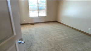 Unfurnished room with light colored carpet and baseboards
