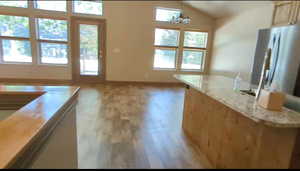 Kitchen featuring plenty of natural light, light wood finished floors, baseboards, and lofted ceiling