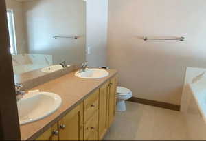 Full bath featuring a tub, toilet, and double vanity
