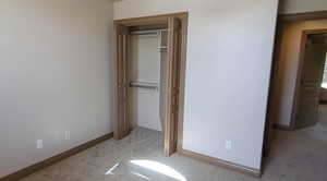 Unfurnished bedroom with carpet flooring, a closet, and baseboards