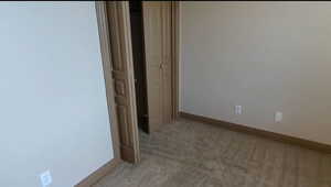 Empty room featuring light carpet and baseboards