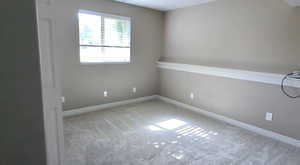 Carpeted empty room featuring baseboards