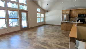 Kitchen with appliances with stainless steel finishes, light wood-style floors, baseboards, a sink, and light countertops