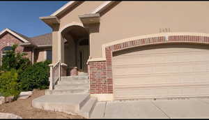 Doorway to property with stucco siding, brick siding, and a garage