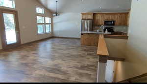 Kitchen with stainless steel appliances, wood finished floors, baseboards, pendant lighting, and a peninsula