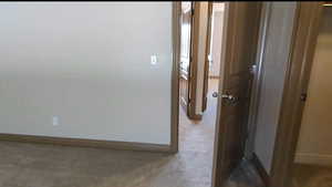 Hallway with baseboards and carpet