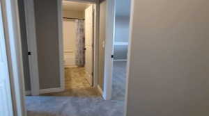 Hall featuring carpet flooring and baseboards
