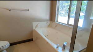 Bathroom featuring a whirlpool tub, toilet, and tile patterned floors