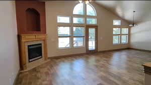 Doorway to outside with light wood-style flooring, a tile fireplace, ceiling fan, baseboards, and a chandelier