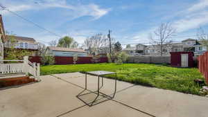 View of patio with a storage unit, an outbuilding, a fenced backyard, and a residential view