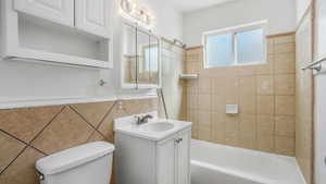 Full bathroom featuring tile walls, bathing tub / shower combination, vanity, and toilet