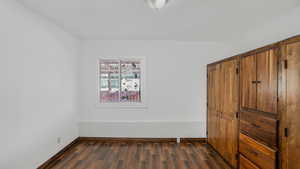 Unfurnished bedroom featuring baseboards and dark wood finished floors