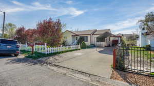 View of front facade with a carport, concrete driveway, and a fenced front yard