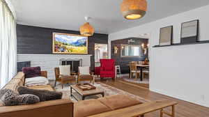 Living room featuring an accent wall, wood finished floors, wood walls, and baseboards